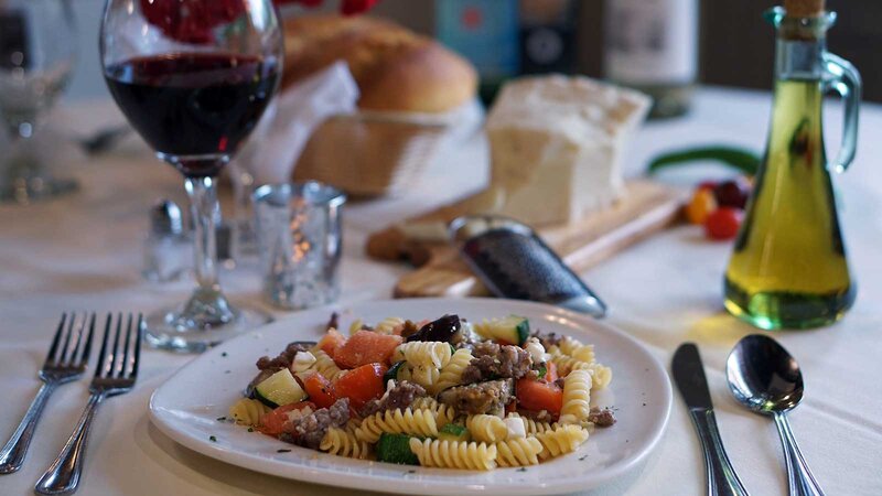 Fusilli entree topped with tomatoes, zucchini and sausage